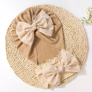 Detail of baby headband and knotted hat with oversized gold polka dot mesh bows