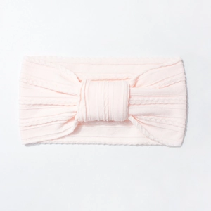 Detailed macro view of soft pink nylon baby headband with fine ribbed knit and knot design