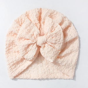Detailed texture of peach bubble crepe baby turban hat with oversized soft fabric bow