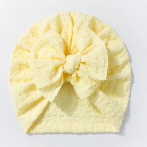 Detail of baby turban hat showing soft yellow seersucker fabric and large decorative bow