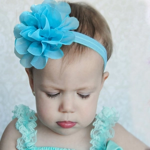 Detail view of baby girl wearing light blue chiffon flower headband and matching lace outfit