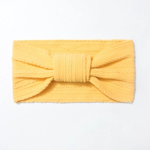 Detail of a bright yellow elastic nylon headband for babies with jacquard knit knot