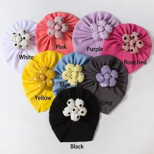 Flat lay of eight colorful waffle knit baby hats with polka dot floral decorations