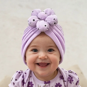 Detail of baby purple turban hat featuring a 3D plush flower and textured waffle fabric