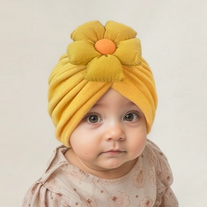 Dettaglio di un cappello a turbante giallo per neonati con un grande fiore in tessuto morbido