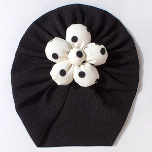 Detailed view of black breathable baby turban hat with white polka dot flower detail