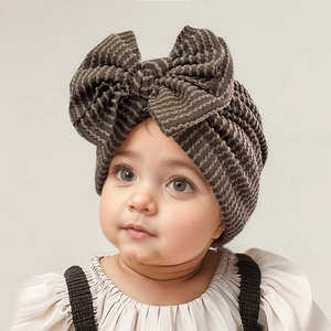 Close-up of olive green newborn hat with large bow and ribbed texture on baby