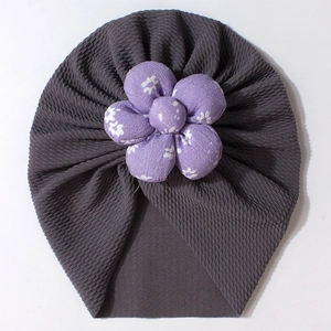 Detail of baby turban hat showing ribbed grey fabric and purple floral decoration