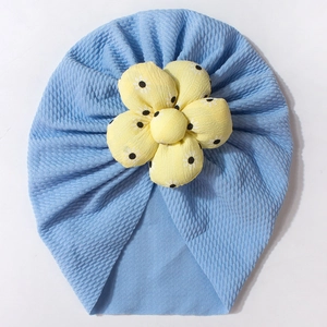 Detail of baby turban hat with sky blue waffle fabric and yellow floral daisy decoration