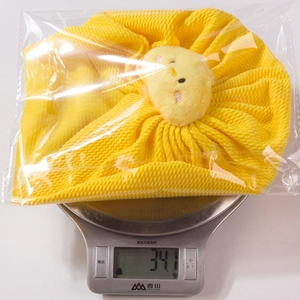 Detail shot of bright yellow waffle knit baby hat with chick mascot on a digital scale