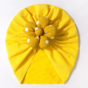 Detail of baby turban hat showing yellow seersucker fabric and large polka dot flower