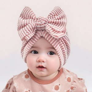 Close-up of pink and white striped newborn hat with large bow detail on infant