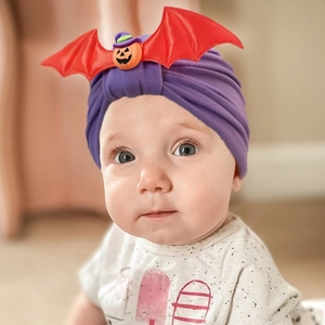 Detail of purple Halloween baby knot hat featuring orange pumpkin and red bat wings
