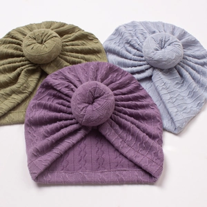 Three soft knitted baby turban hats in green, purple, and blue with donut knot design