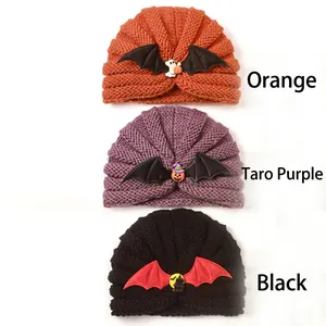Close-up of Halloween baby knitted hats with bat wings and pumpkin ghost charms