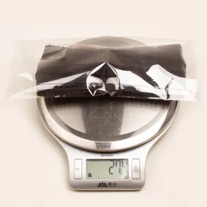 Detail shot of solid black baby bow headband weighing 27.4g on a digital scale