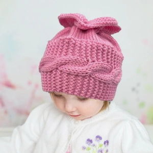 Détail du bonnet en tricot rose pour bébé avec haut volanté et maille torsadée