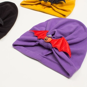 Detailed shot of purple Halloween baby knot hat with pumpkin and red bat wing decoration