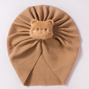 Brown waffle cotton baby hat featuring a cute plush bear ornament on a white background