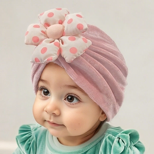 Detailed view of plush pink velvet baby turban hat with oversized polka dot floral decor