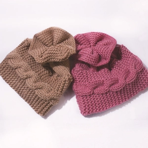 Détail du motif de maille torsadée épaisse et texture des bonnets d'hiver pour bébé en rose