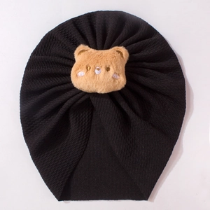 Detail of black ribbed knit baby turban hat featuring a cute brown plush bear patch
