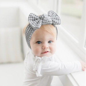 Detailed close-up of grey knitted baby headband with a soft waffle texture and bow