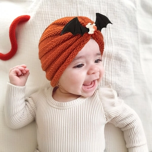 Detailed knit texture of baby pumpkin hat featuring black bat wing embellishments
