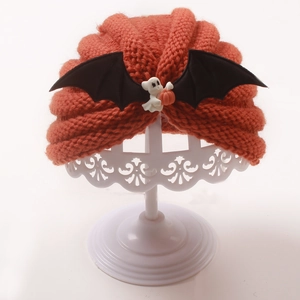 Detail of orange ribbed knit baby hat with black bat wings and pumpkin ghost accessory