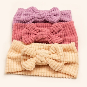 Three soft waffle knit baby headbands with large bows in purple, rose pink and beige
