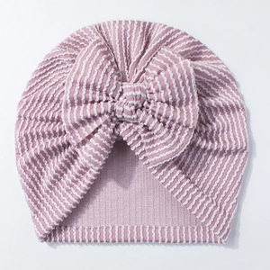 Close-up of pink and white striped newborn turban hat with large knit bow decoration