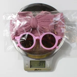 Pink baby headband and sunglasses set shown on a scale weighing 37.7 grams