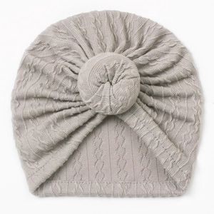 Detail of grey cable knit baby donut hat featuring a soft twisted knot design