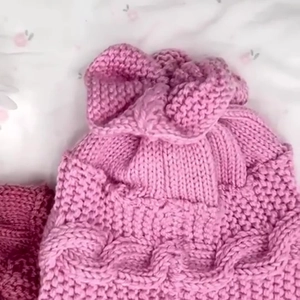 Détail du bonnet tricoté rose pour bébé avec motif plissé et texture moelleuse