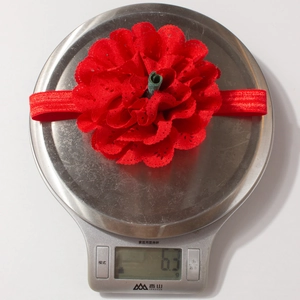 Detailaufnahme eines leichten 6,3 g roten Spitzenblumen-Babystirnbands auf einer Waage