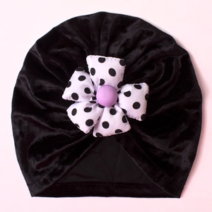 Detail of baby velvet turban hat featuring a large black and white polka dot flower