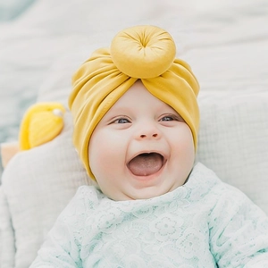 Detail der weichen senfgelben Baby Turbanmütze mit Donut-Knoten und elastischem Stoff