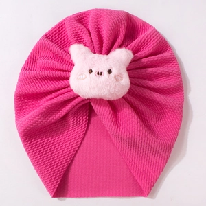 Detail view of pink baby turban with waffle texture and plush pig ornament
