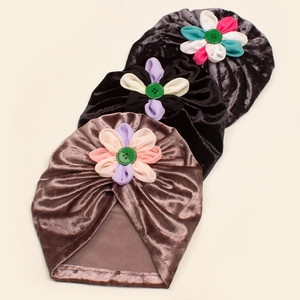 Vue détaillée des turbans en velours pour bébé avec fleurs en tissu et boutons décoratifs