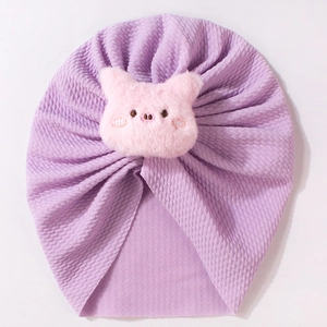 Close-up of lilac waffle knit baby turban hat with a cute pink plush piglet decoration