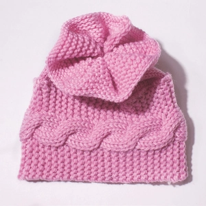 Détail du bonnet en tricot rose pour bébé avec motif torsadé et texture chaude