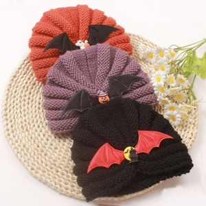 Halloween baby knitted beanie set with pumpkin and bat pendants on straw mat