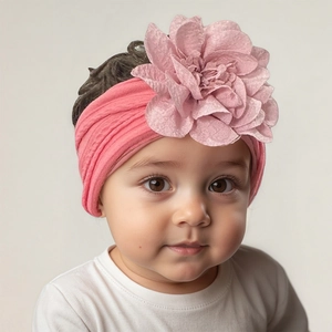 Détail d'un bandeau pour bébé en jacquard rose avec une grande fleur faite à la main