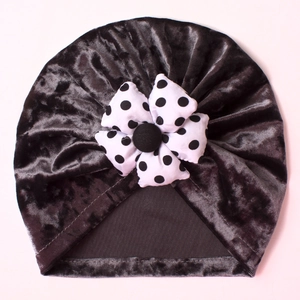Detailed view of black velvet baby turban with a white polka dot fabric flower accent