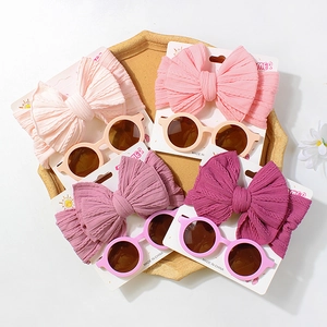 Close-up of baby ribbed bow headbands and vintage sunglasses in soft pink tones