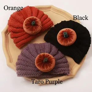 Detailed knit texture of orange, black and purple baby pumpkin hats on a tray
