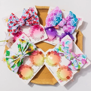 Four sets of floral baby bow headbands and matching daisy sunglasses on a tray