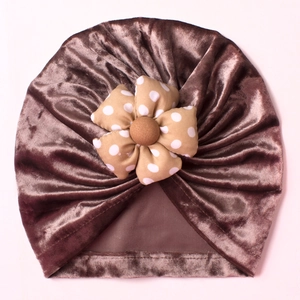 Detail of baby velvet turban hat with soft pleats and a decorative polka dot fabric flower