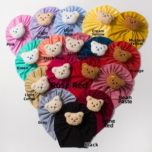 Flat lay of soft baby beanies with teddy bear ears arranged in heart shape across 17 colors