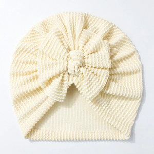 Detailed close-up of light yellow striped baby hat with a large decorative bow
